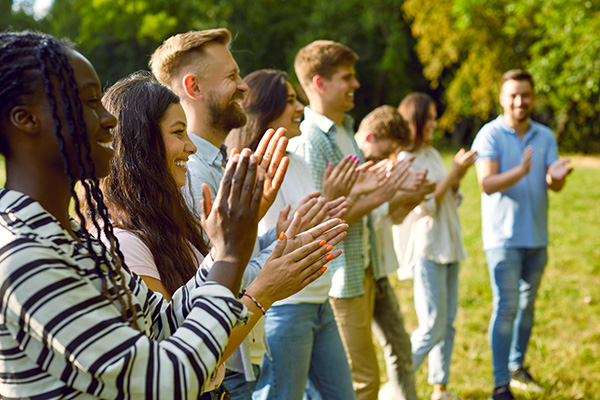 People clapping at an outdoor event.