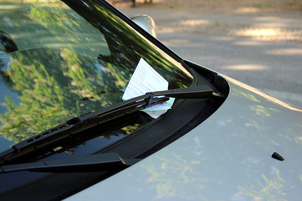 A citation under the windshield wiper on a car.