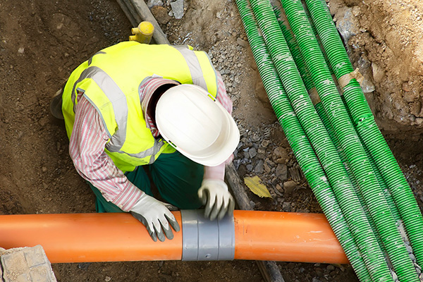 worker installing hdpe corrugated pipe with double wall strength at the construction site on street city